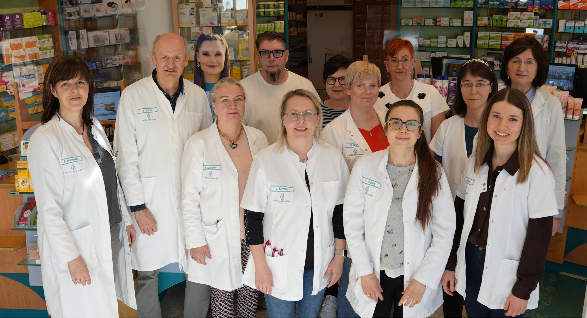 Gruppe von 12 Personen in weißen Kitteln in einer Apotheke